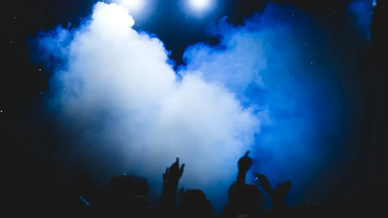 Thick cloud of fog lit by blue stage lights above a crowd