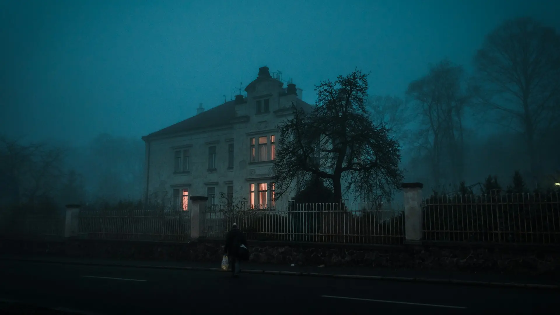 Old mansion with lit windows on a foggy night