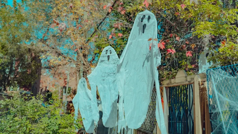 Fabric ghost decorations hanging from a tree outdoors